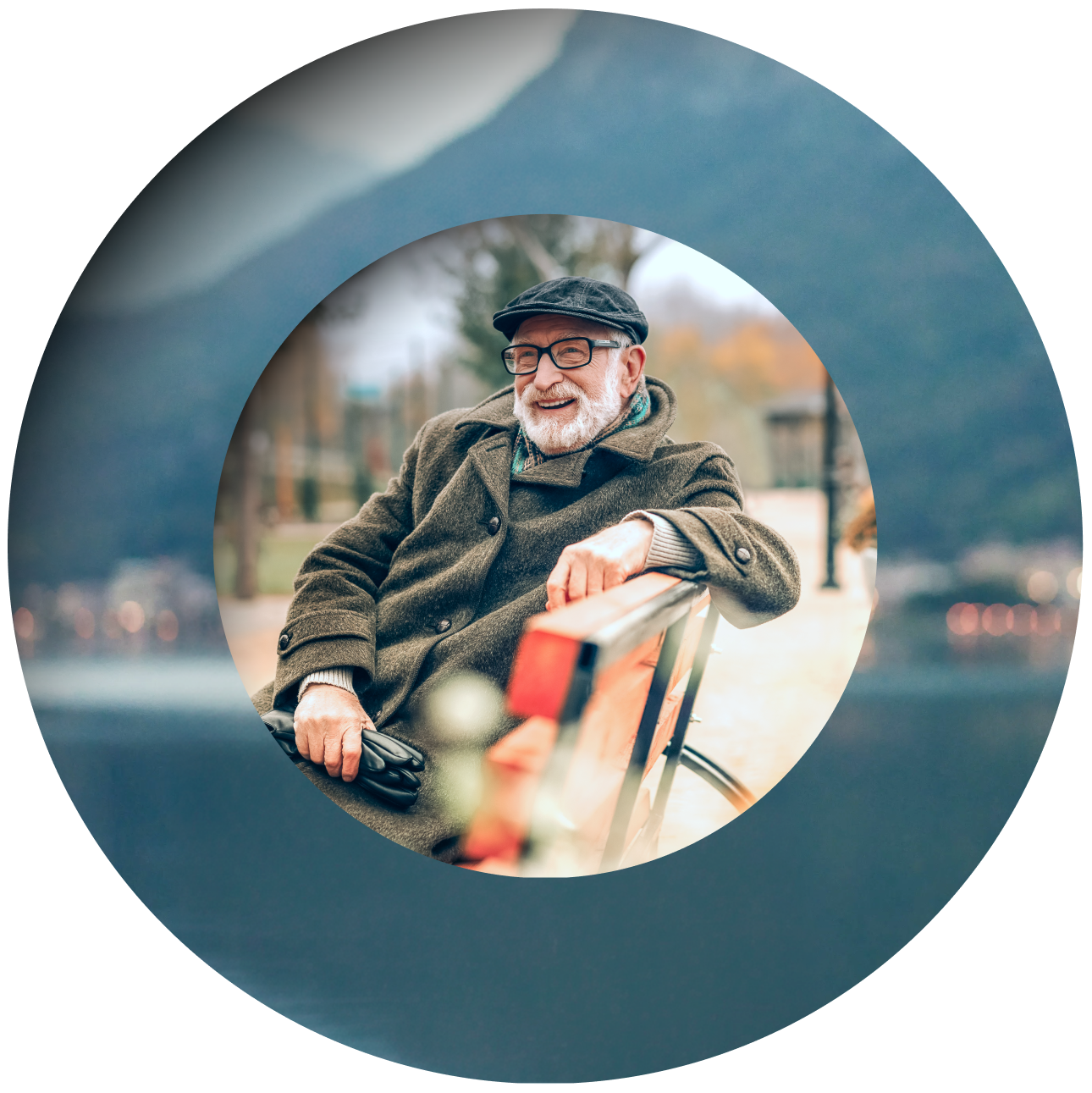 An elderly man in a hat and coat smiles while sitting on a park bench, viewed through a circular frame with a soft blue border.